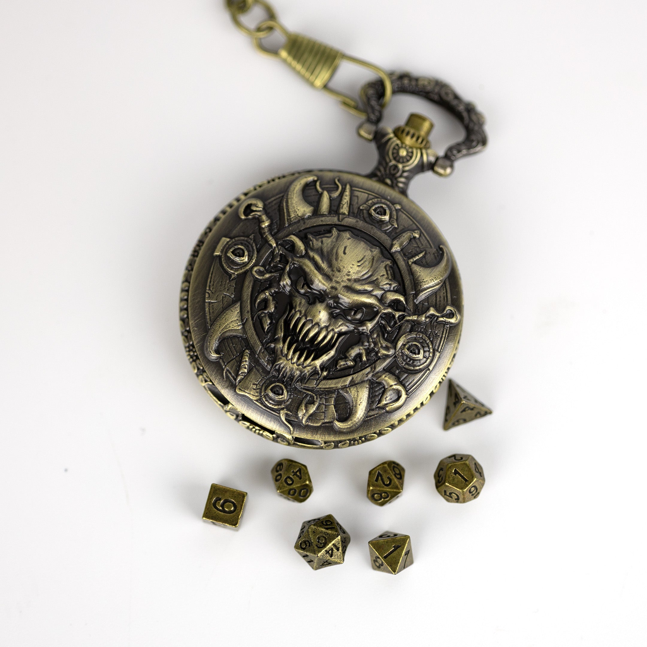 Bronze pocket watch with demon design and surrounding dice on a white background